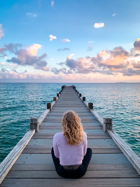 海の橋に座って海を眺める女性